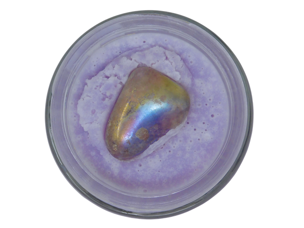 Iridescent stone in a container with purple body butter on a white background