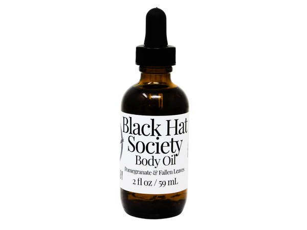 2 oz brown glass dropper bottle with white label that reads: Black Hat Society Body Oil. Pomegranate & Fallen leaves. 