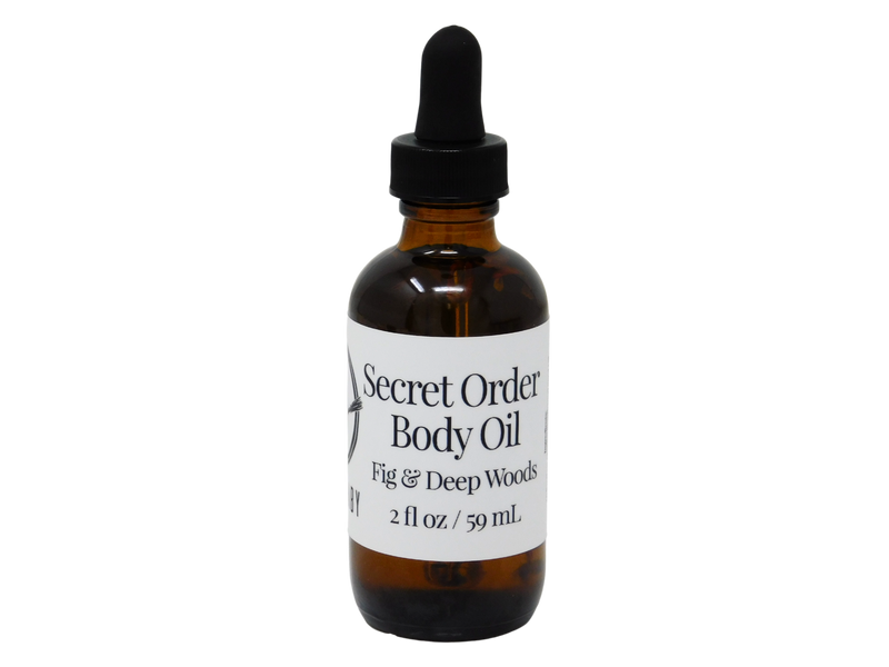 photo of secret order body oil packaged in 2 oz glass dropper bottle with white label that reads Secret Order Body Oil. Fig & Deep Woods.